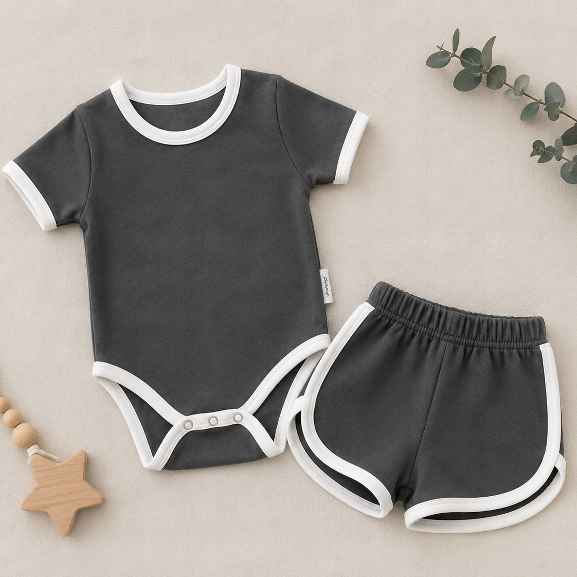 Baby outfit set with dark gray bodysuit and shorts on a beige background